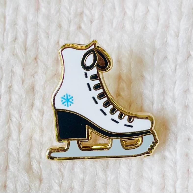 White and black ice skate with blue snowflake detail gold hard enamel mini pin