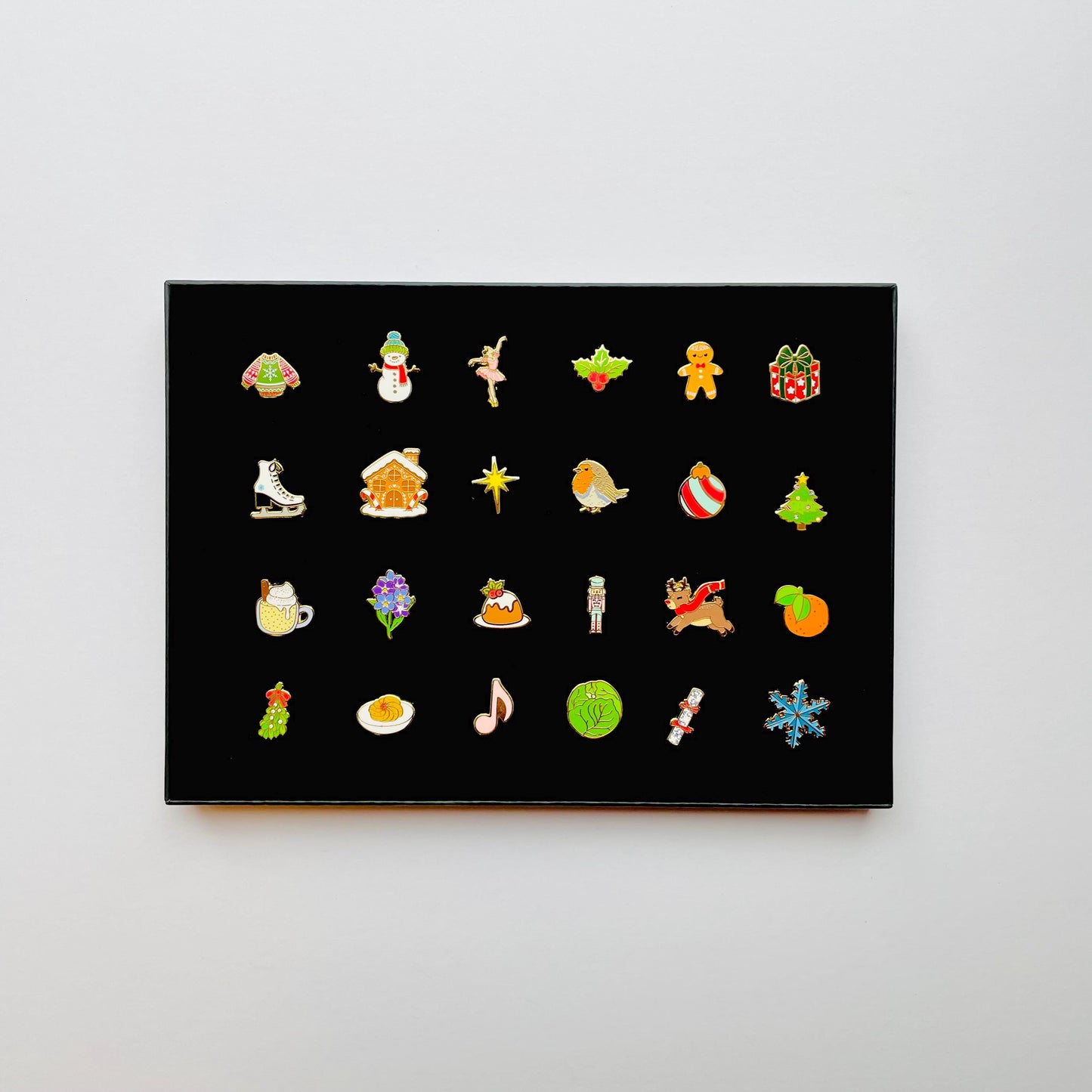 24 Christmas themed gold hard enamel pins in a black gift box