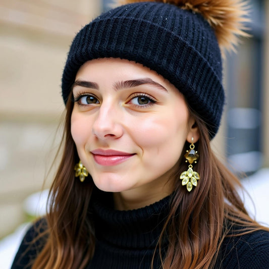A young woman with long brown hair wearing a black knit hat and large gold earrings, smiling at the camera.