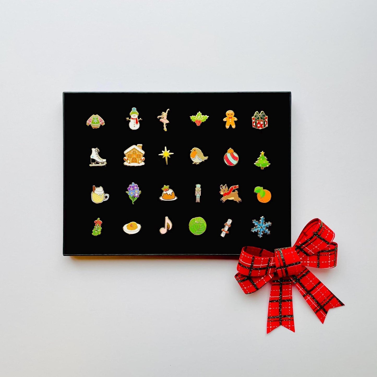 24 Christmas themed gold hard enamel pins in a black gift box
