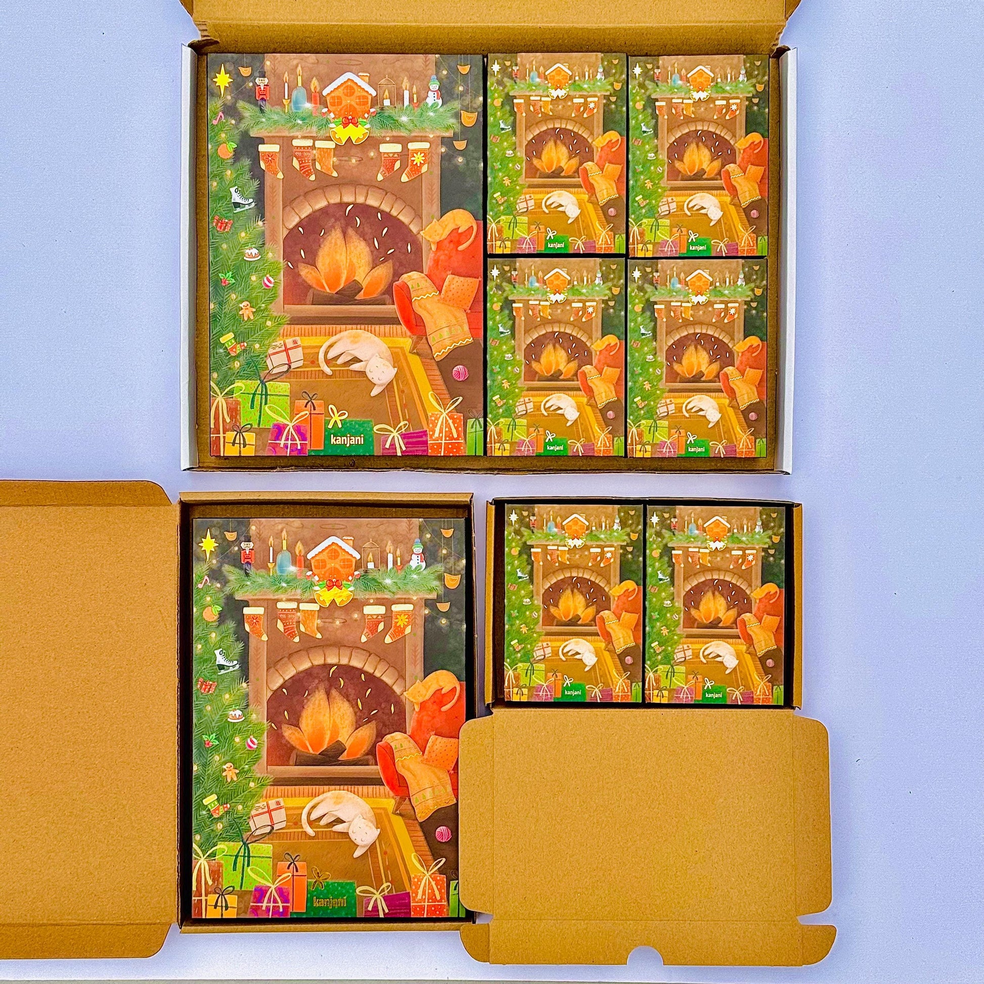 a collection of Christmas-themed greeting cards displayed in a cardboard box. The cards feature illustrations of a fireplace, Santa Claus, and various holiday decorations, creating a festive atmosphere.
