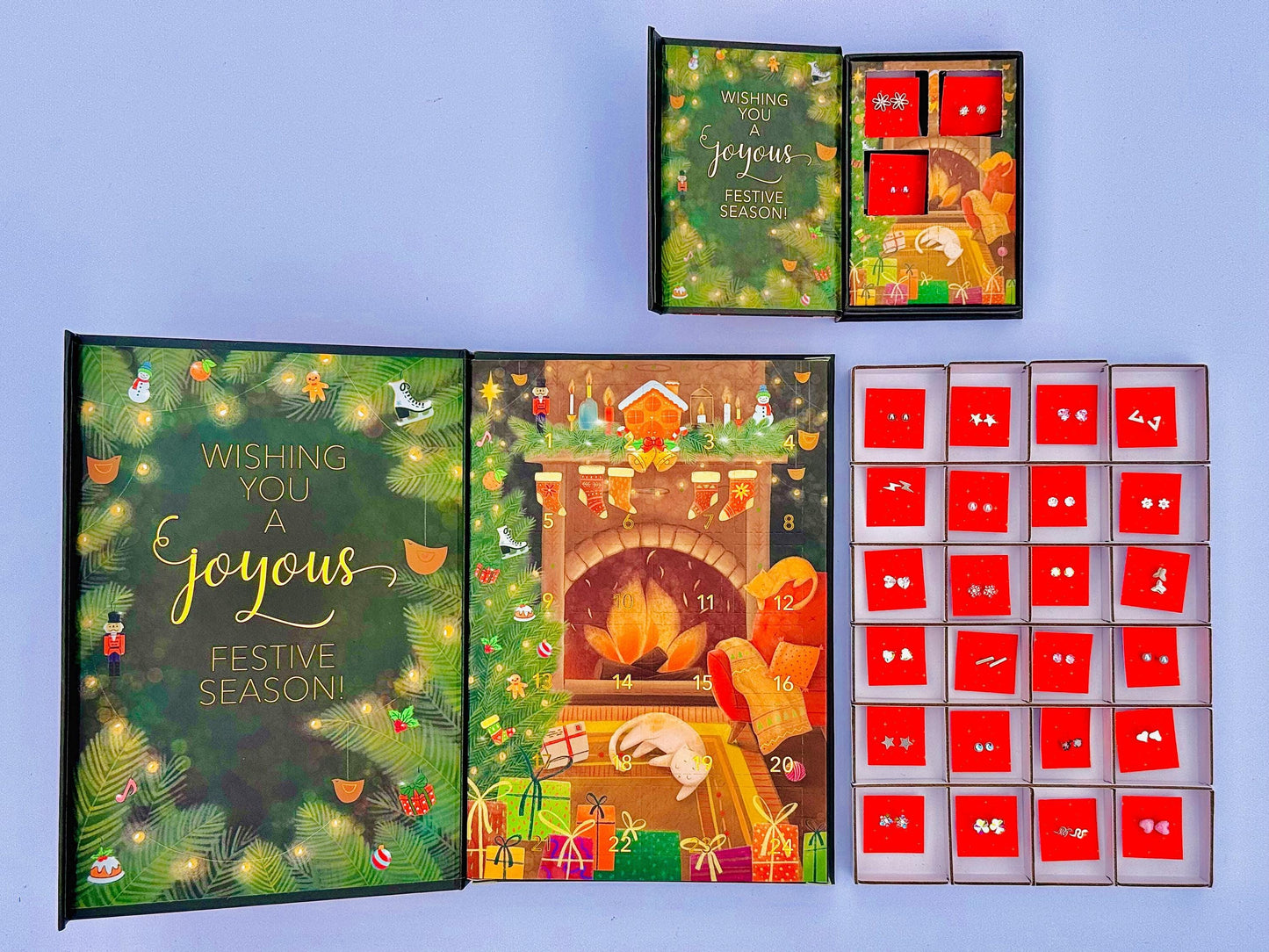 a festive holiday-themed advent calendar, a set of red boxes with earrings, and a greeting card with a Christmas tree and a person.