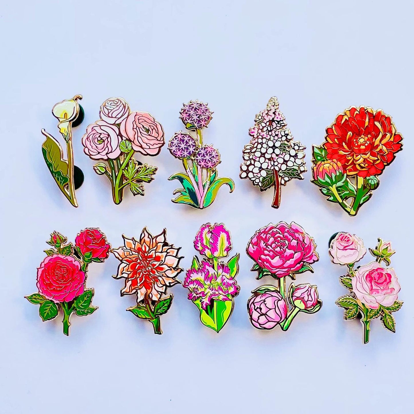 a collection of colorful enamel pins featuring various flowers, including roses, peonies, and other blooms.