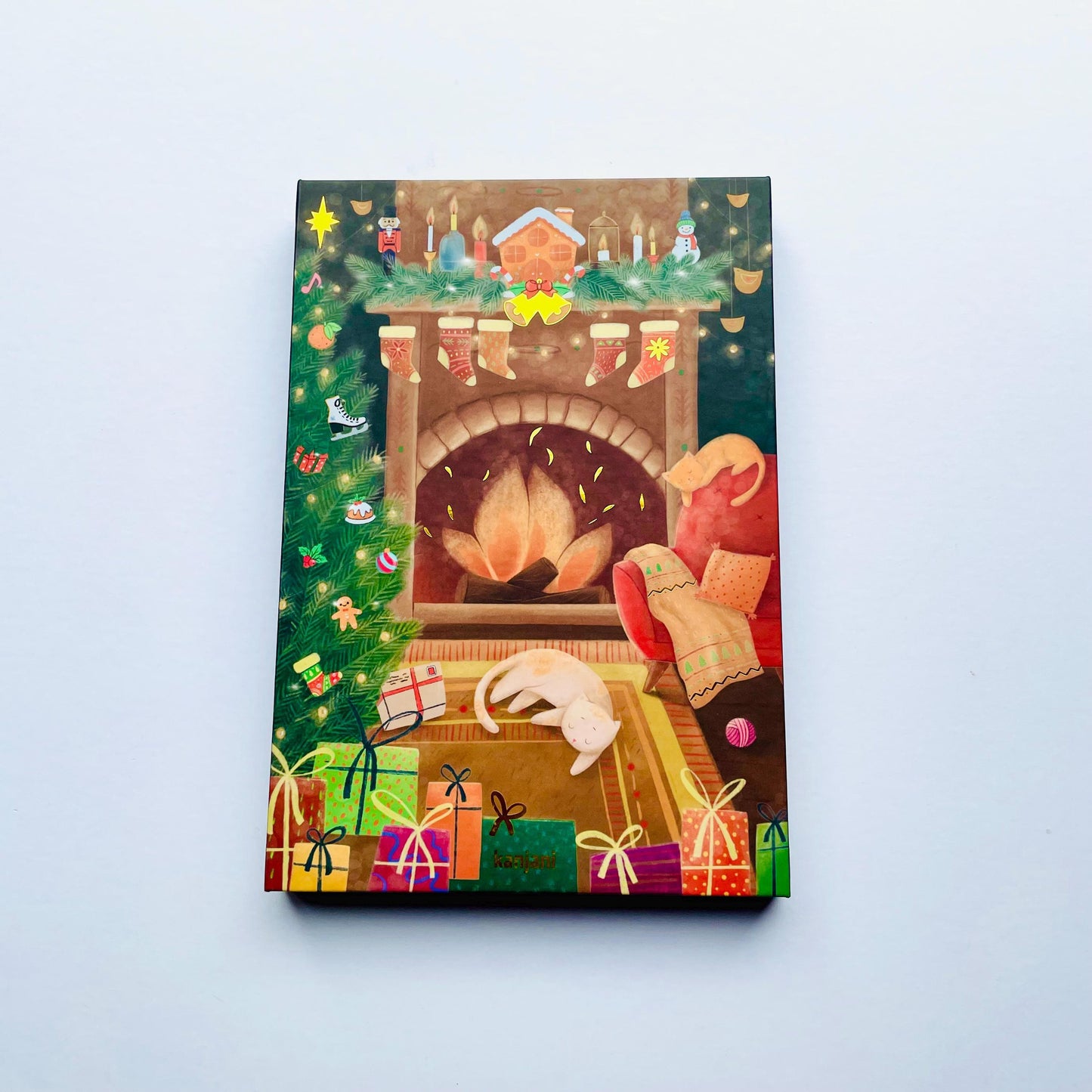 A colorful illustration depicting a cozy Christmas scene with a fireplace, presents, and a cat sitting by the fire.