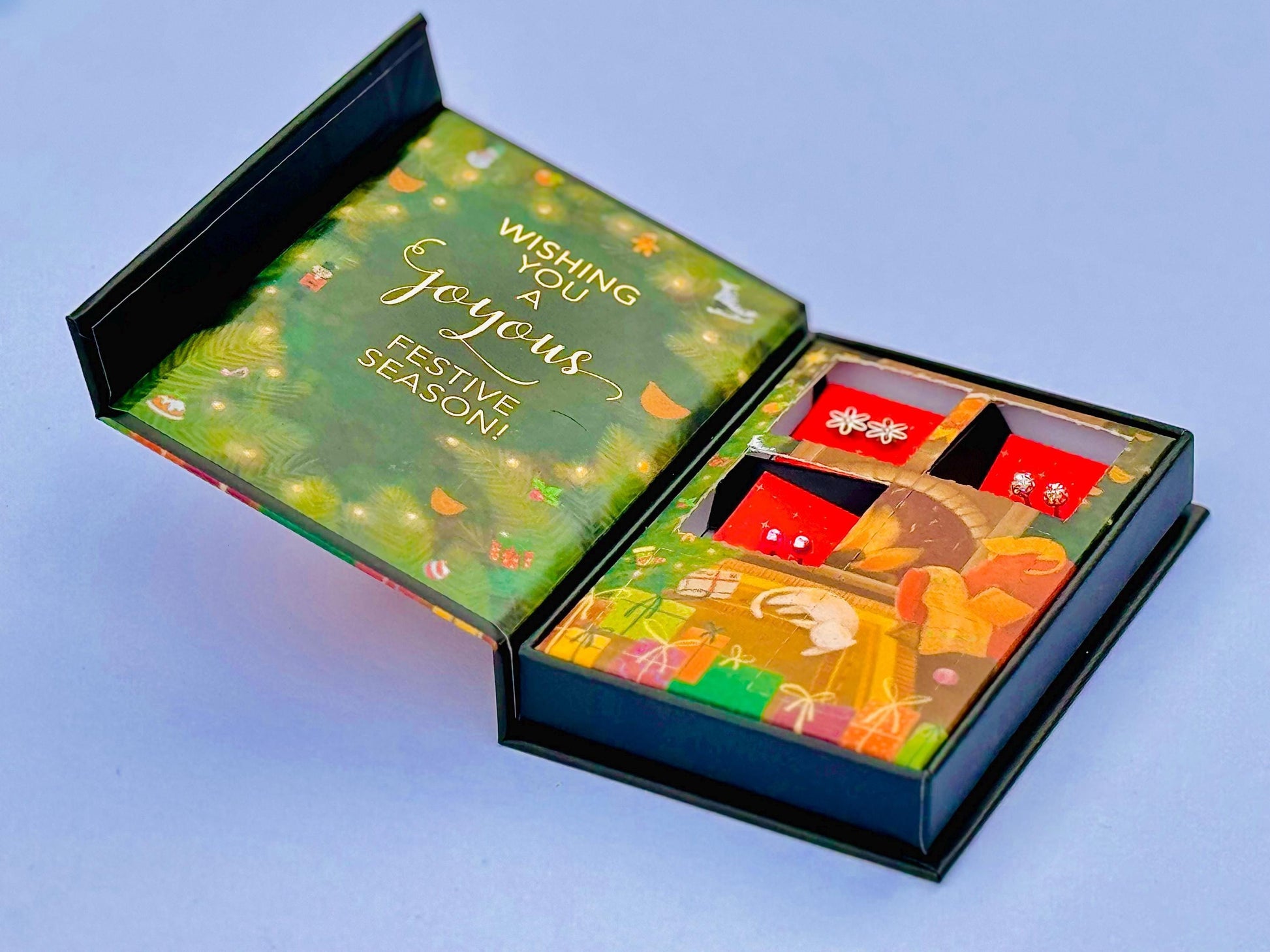 a gift box with a festive design, containing a pair of earrings and a card.
