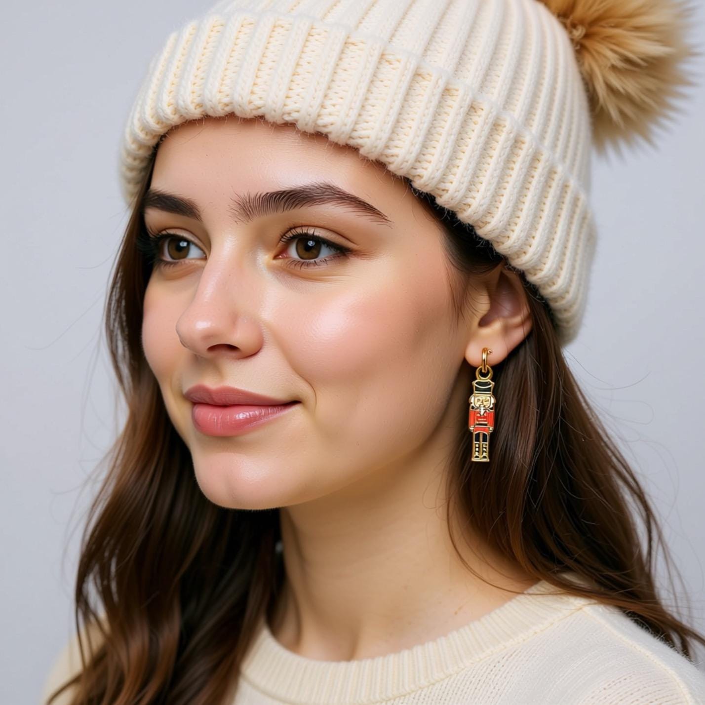 A young woman with brown hair wearing a white knit hat and earrings, smiling at the camera.