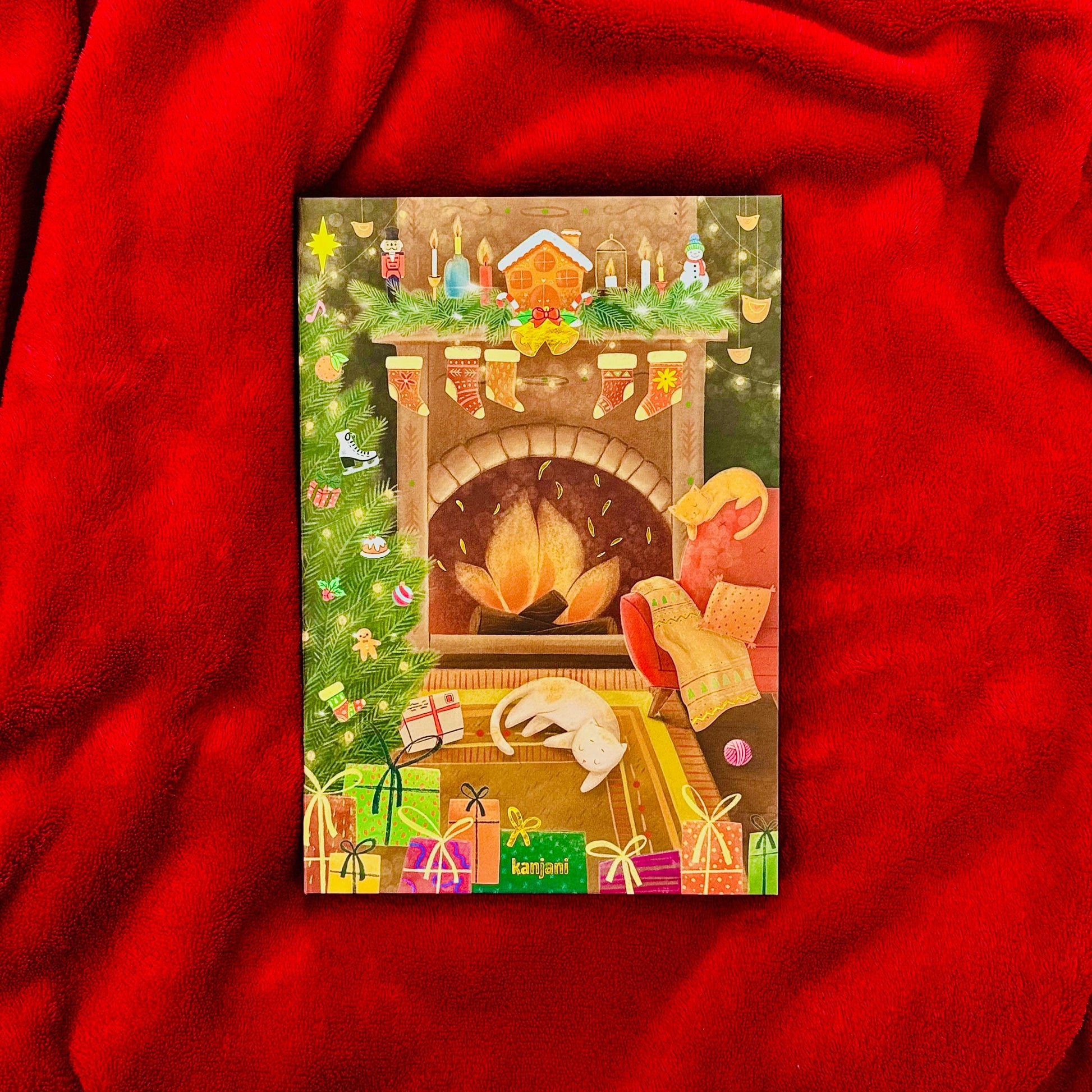 A colorful Christmas card with a fireplace, presents, and a cat resting on a rug, all set against a red background.