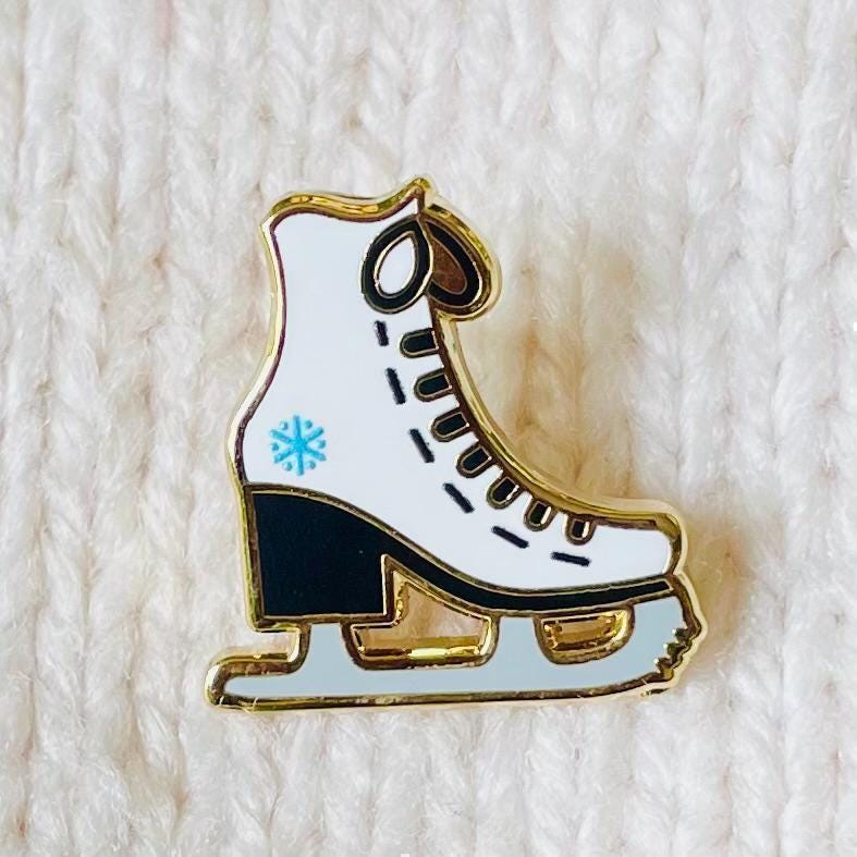 White and black ice skate with blue snowflake detail gold hard enamel mini pin