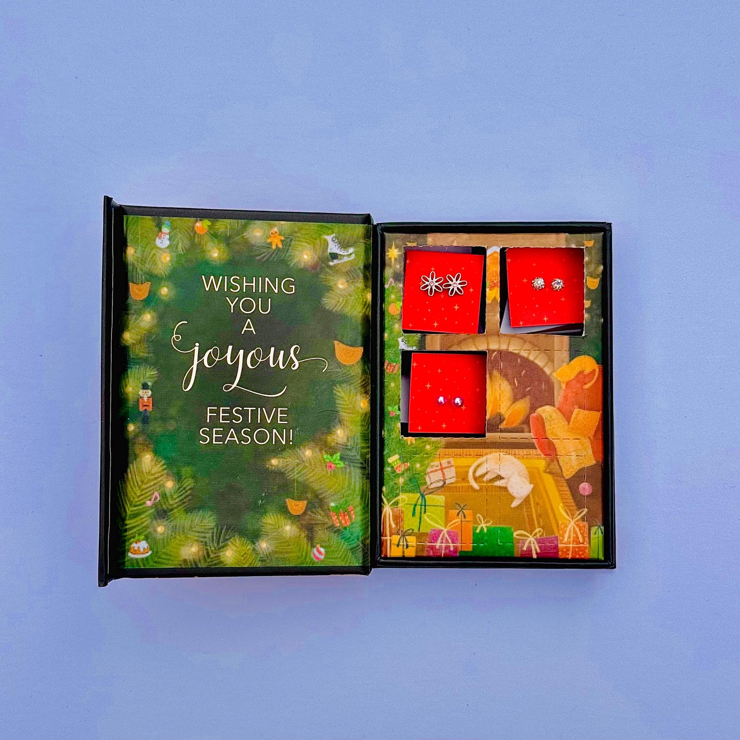 A gift set with a card that wishes the recipient a joyful festive season, accompanied by a small box containing two earrings.