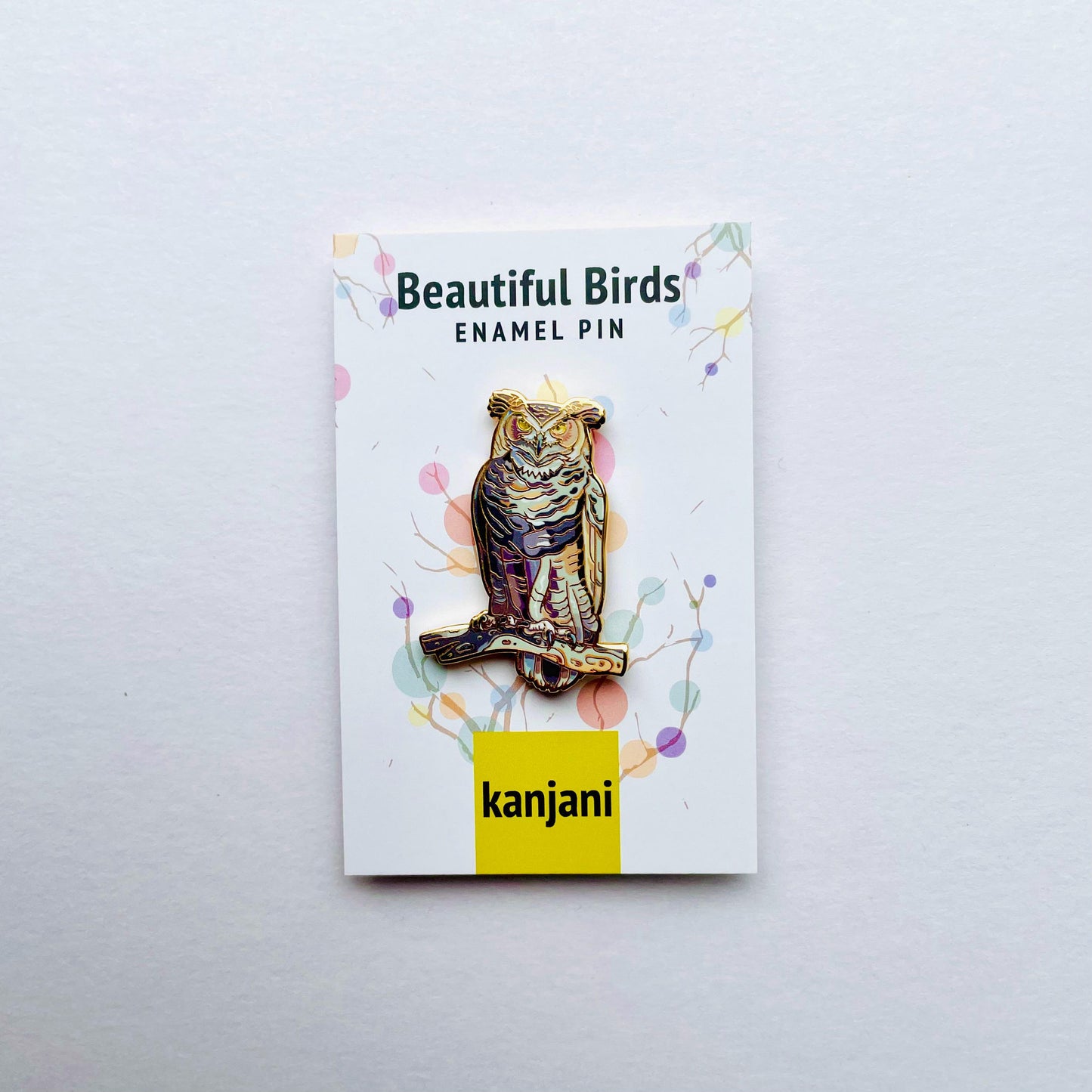 an ornate pin with a colorful owl design, displayed on a white background.