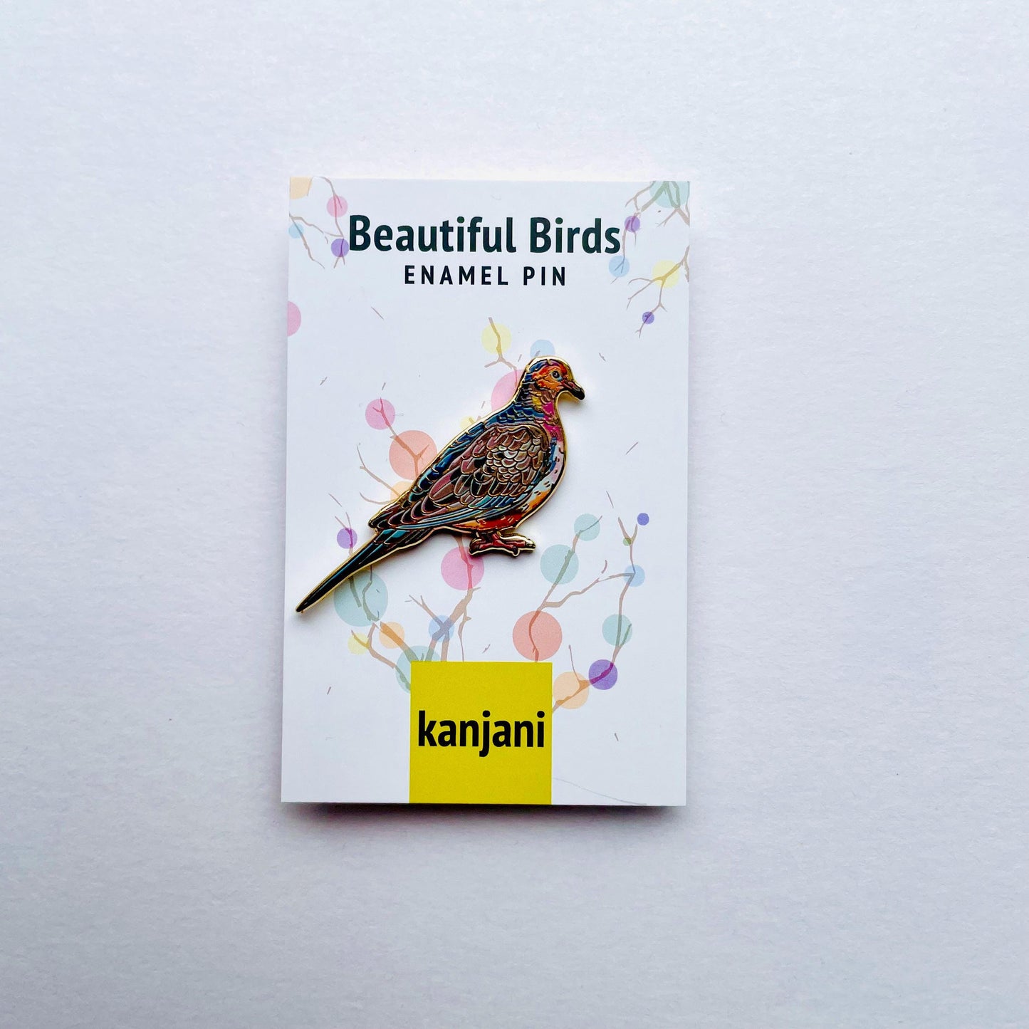 a colorful enamel pin of a bird, which is part of the "Beautiful Birds" series.