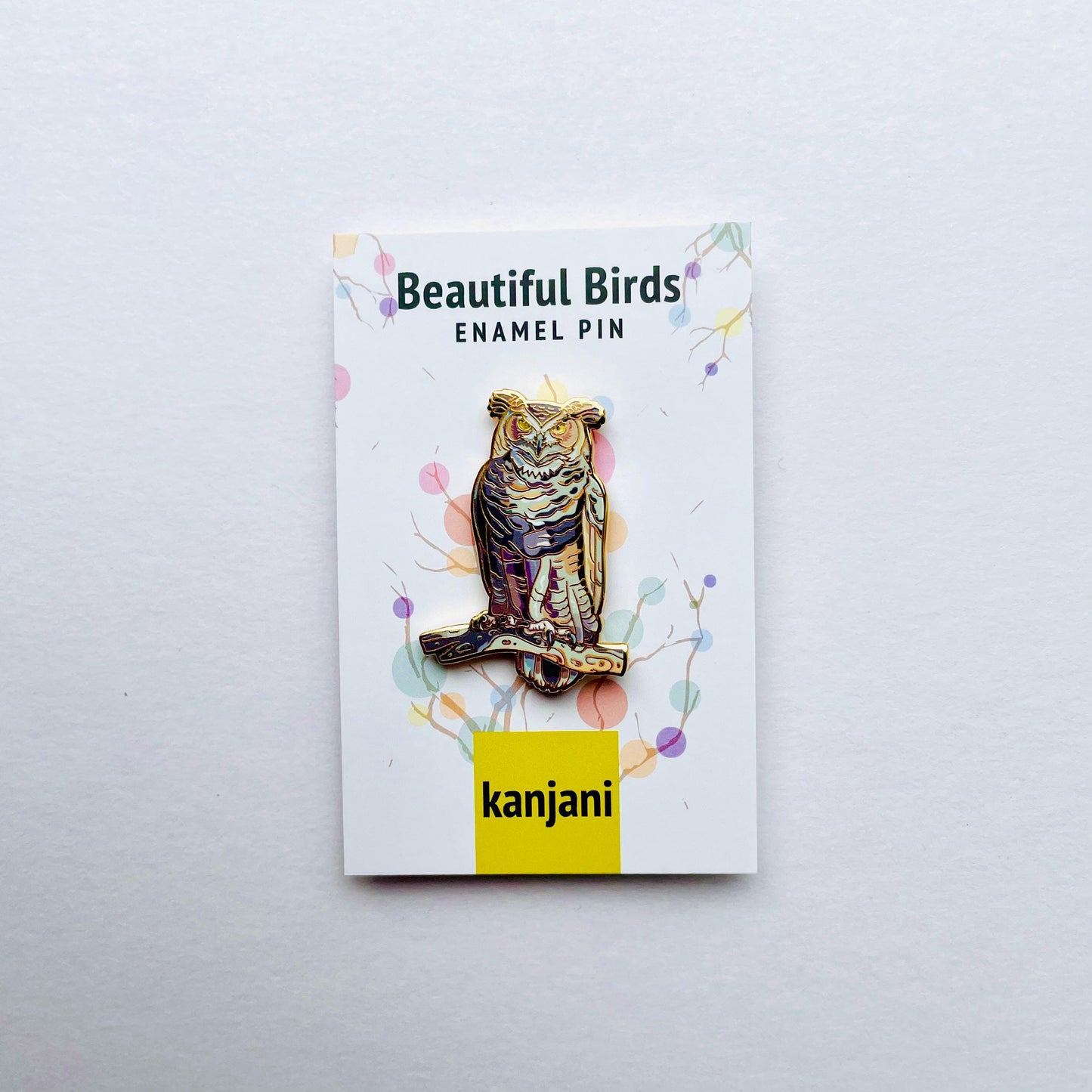 an ornate pin with a colorful owl design, displayed on a white background.