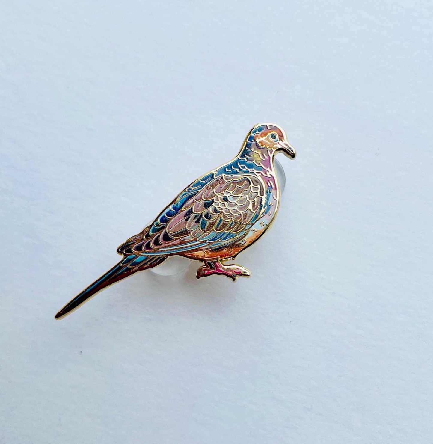 A colorful bird pin is displayed against a plain white background.