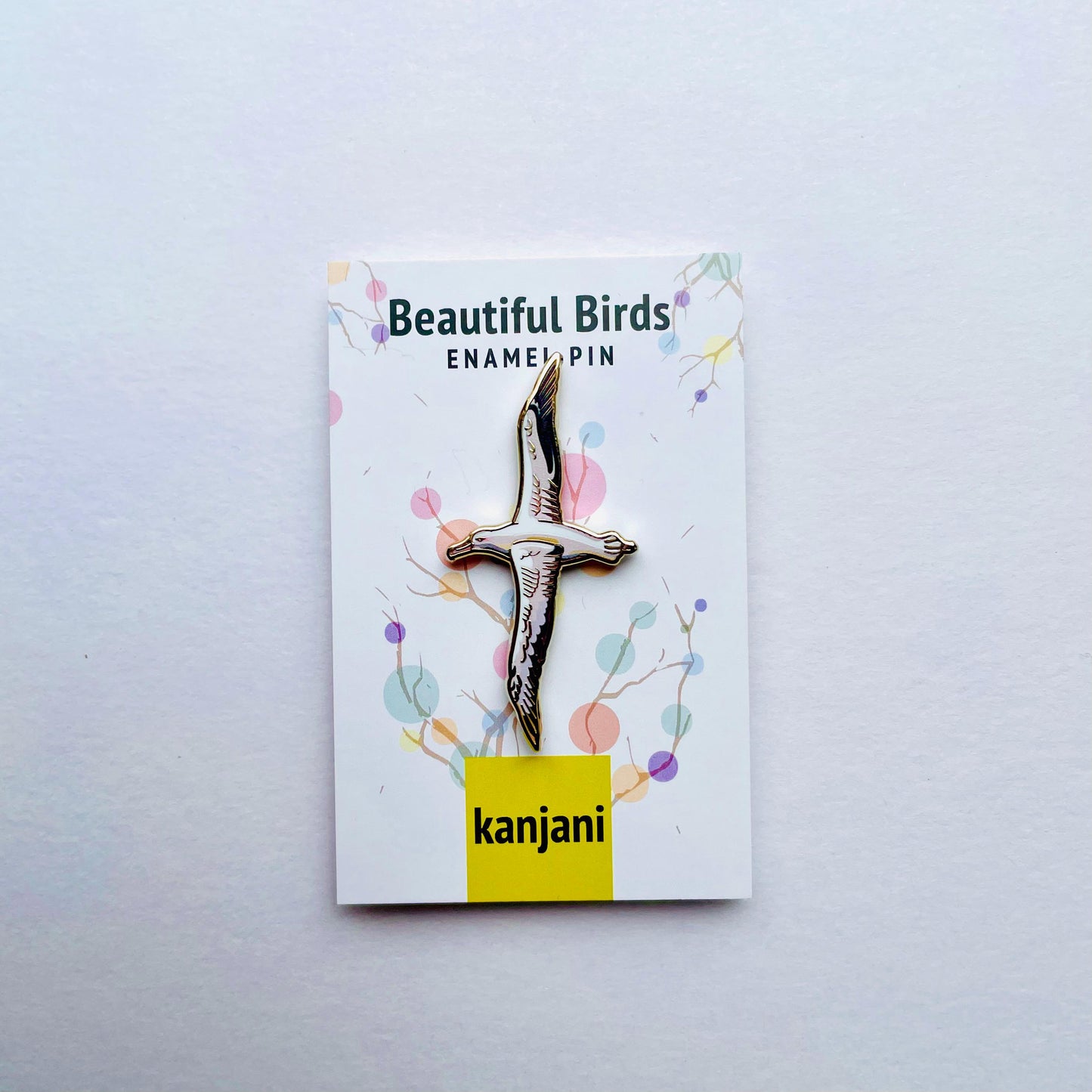 a pin with a bird design, placed on a white background.