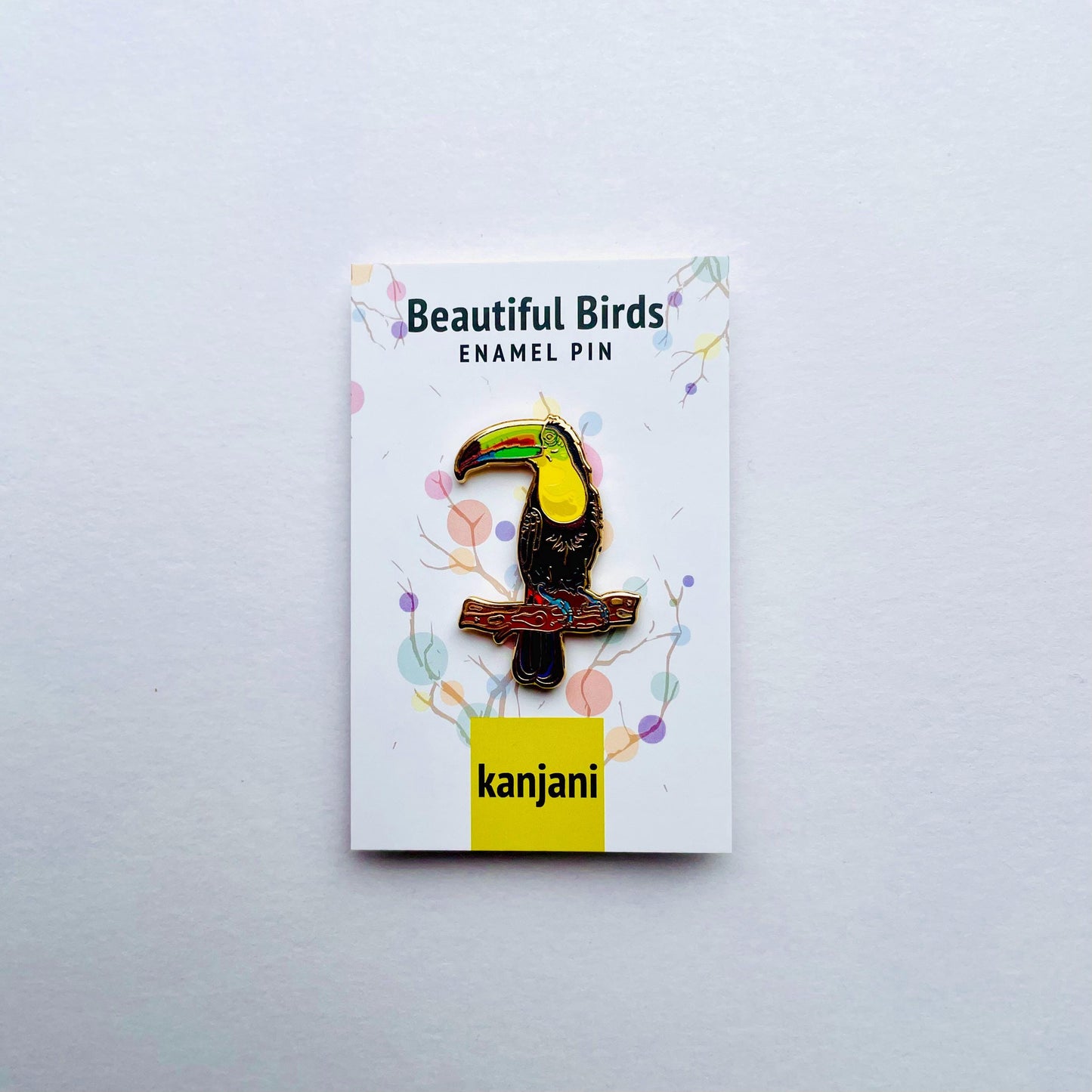 a colorful enamel pin of a toucan bird, which is a beautiful bird.