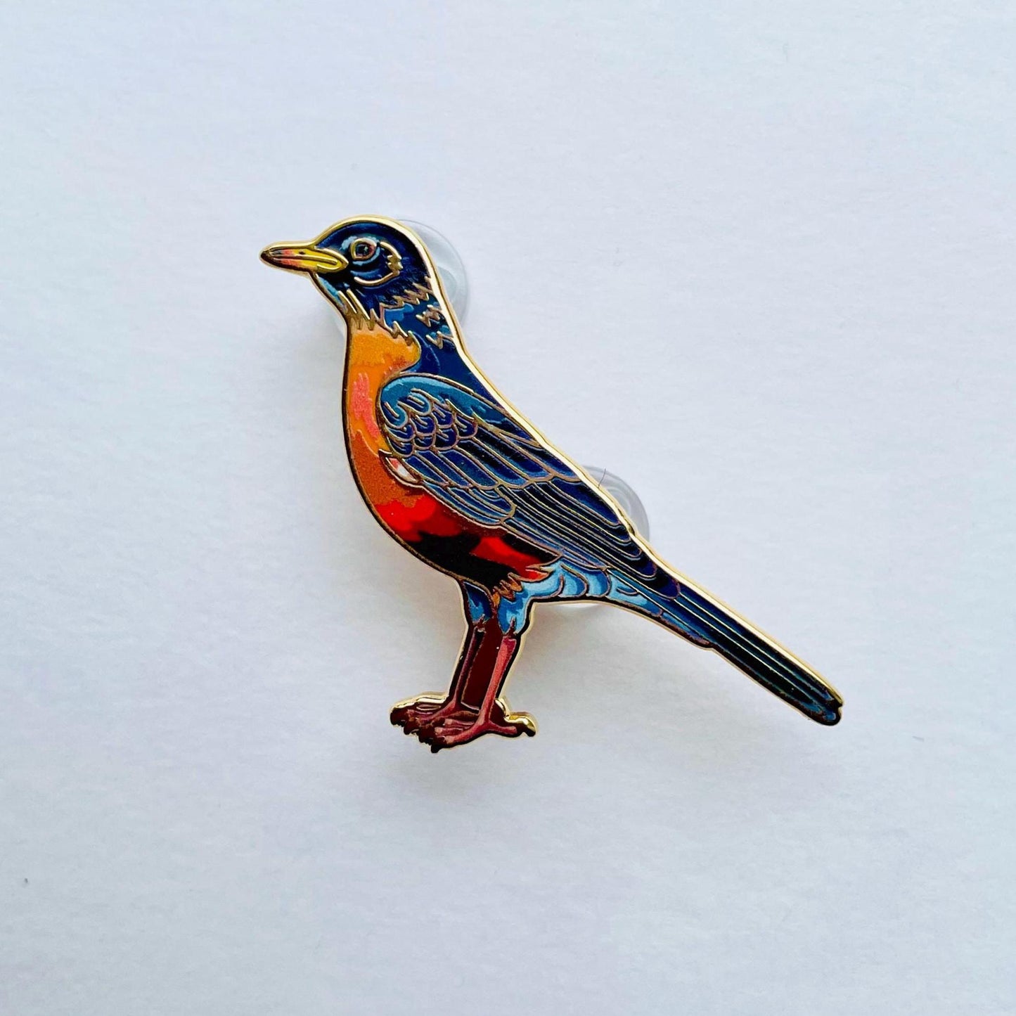 A colorful bird pin is shown against a plain white background.