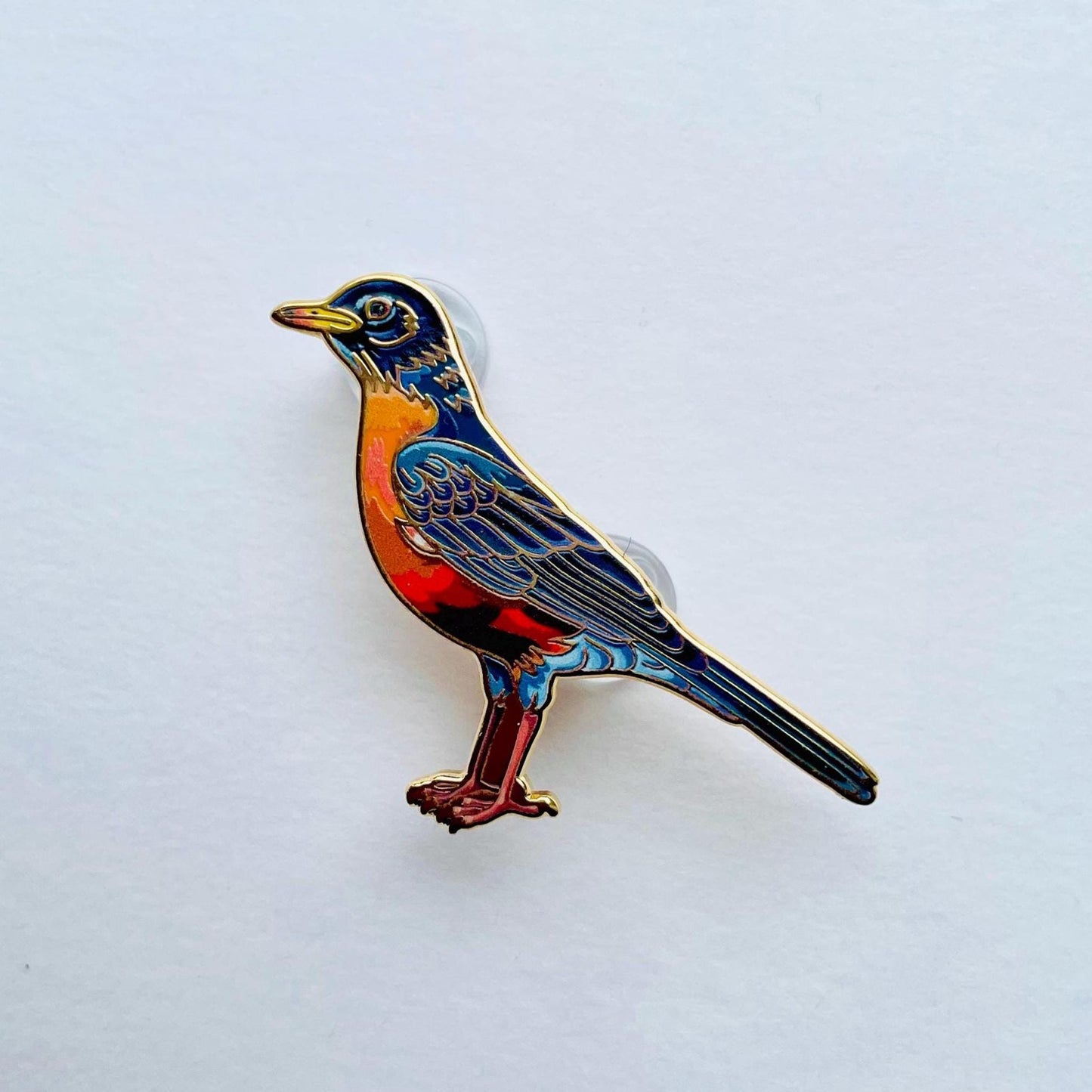 A colorful bird pin is shown against a plain white background.